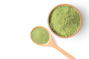 Green Spirulina powder in wooden bowl and spoon isolated on white background. Copy space. Top view. making spirulina juice