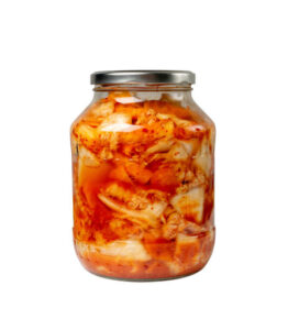 Kimchee in a glass jar isolated. Spicy kimchi, hot fermented napa cabbage, traditional kimchi, Korean winter food kimchi, kimchee on white background side view