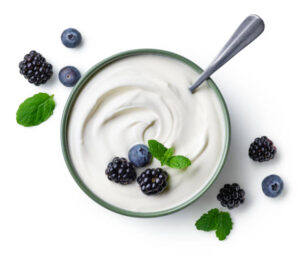 Green bowl of greek yogurt and fresh berries isolated on white background, top view