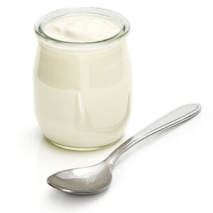 A jar of plain yogurt with a silver spoon.