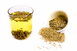 Herbal detoxifying drink isolated on white i.e. Jeera water with some raw organic cumin in a glass bowl.