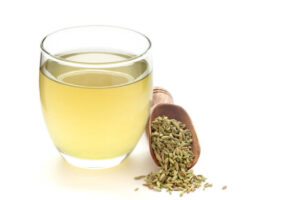 Close-Up of original organic boiled water (Tea or kada ) with Sonf or Fennel seed ( Foeniculum vulgare ) in a transparent glass cup over white background. Original residue in bottom of tea cup