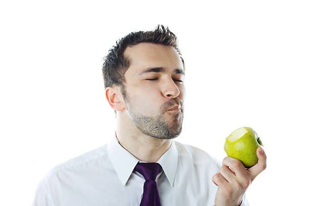 Close-up of young businessman eating apple. Isolated on white.