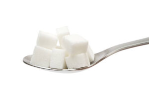 Several sugar cubes on a silver spoon. Isolated on a white background.