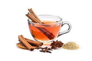 Cup of aromatic tea on white background. At the base of the cup are cinnamon sticks, dried orange slice, cloves, star anise and a little heap of dried camomile. Also inside the cup are two cinnamon sticks. Predominant color: Brown. DSRL studio photo taken with Canon EOS 5D Mk II and EF 100mm f/2.8L Macro IS USM